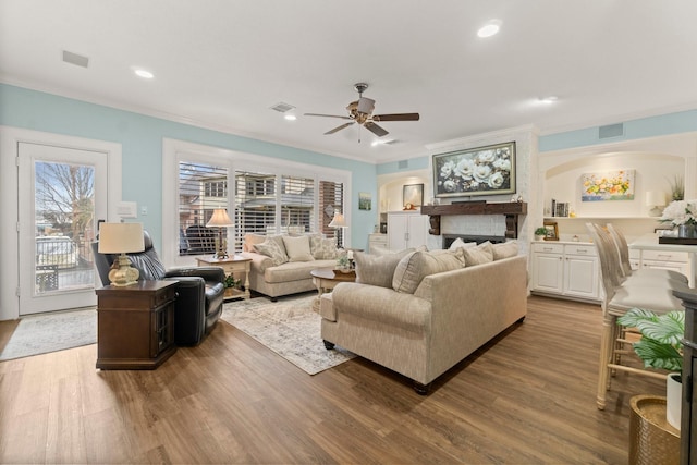 living room with recessed lighting, wood finished floors, visible vents, and crown molding