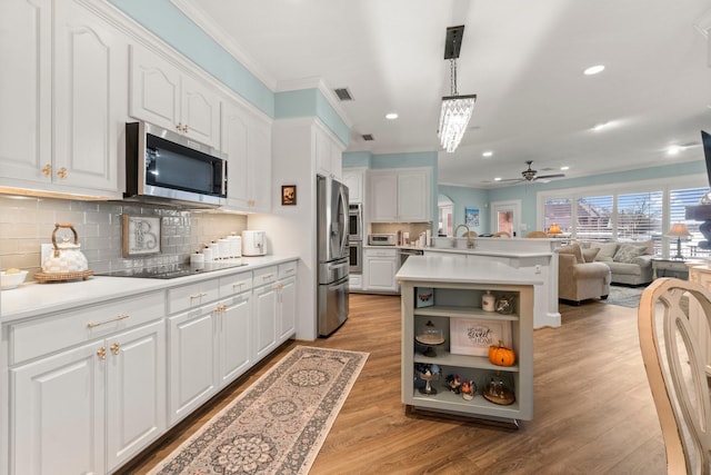 kitchen with visible vents, white cabinets, open floor plan, appliances with stainless steel finishes, and backsplash