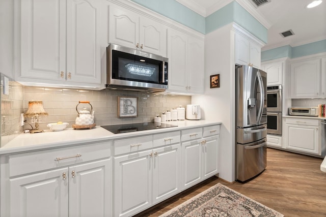 kitchen featuring stainless steel appliances, visible vents, crown molding, and white cabinetry