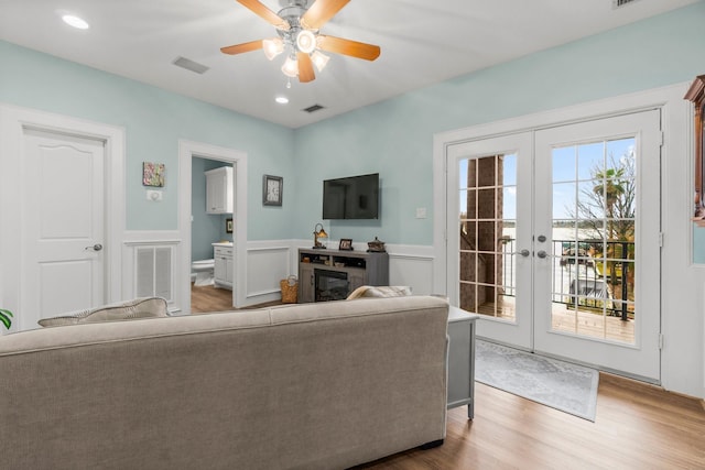 living room featuring wainscoting, visible vents, wood finished floors, and french doors