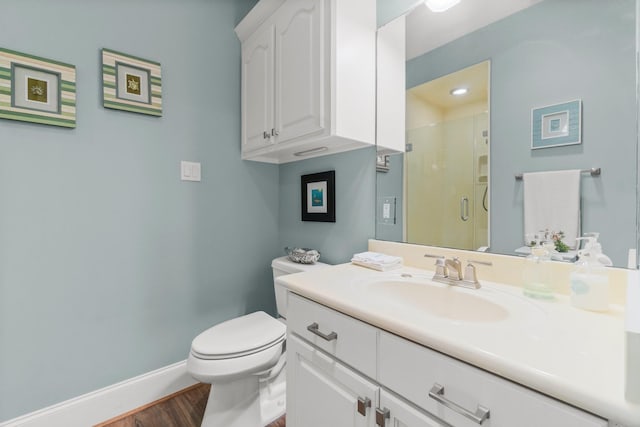 full bathroom featuring toilet, wood finished floors, vanity, baseboards, and a stall shower