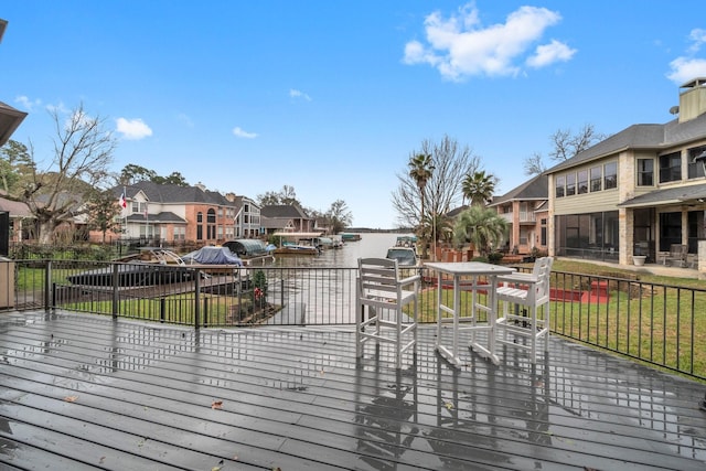 wooden terrace with a residential view, a water view, and a lawn