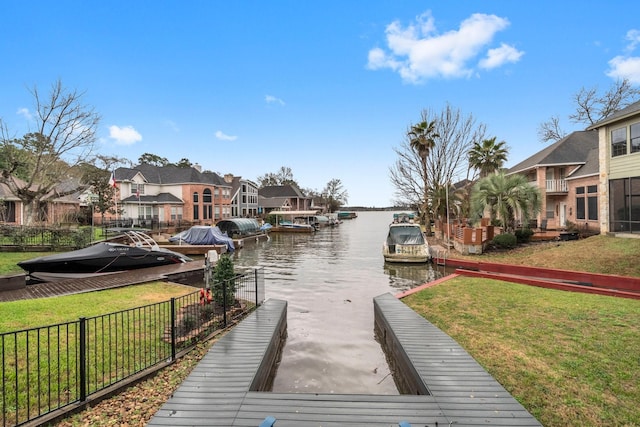 dock area with a lawn, a water view, and a residential view