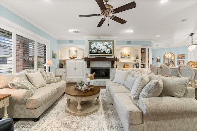 living area with recessed lighting, visible vents, crown molding, and a glass covered fireplace