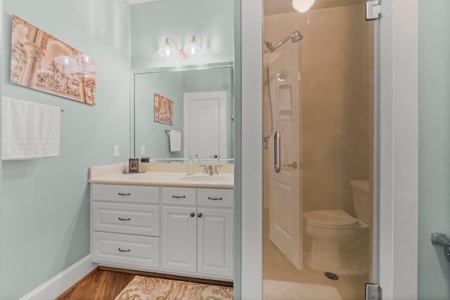 full bath with toilet, wood finished floors, vanity, baseboards, and a stall shower