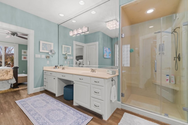 ensuite bathroom featuring ensuite bathroom, wood finished floors, a stall shower, and a sink