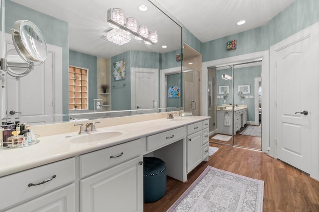 bathroom with double vanity, a stall shower, a sink, and wood finished floors