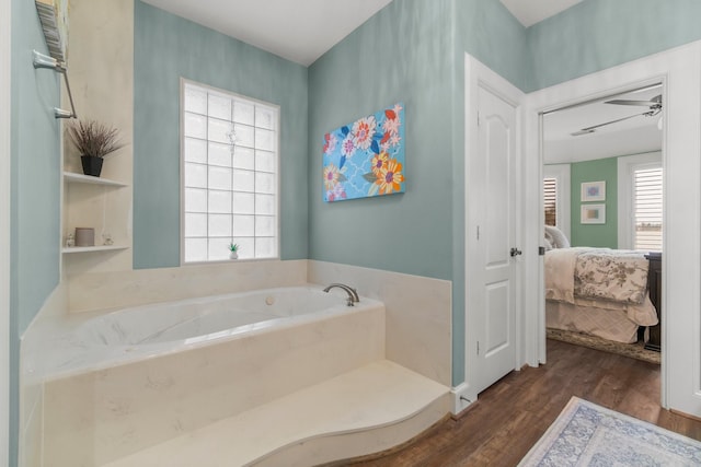 bathroom with a bath, a healthy amount of sunlight, ensuite bath, and wood finished floors