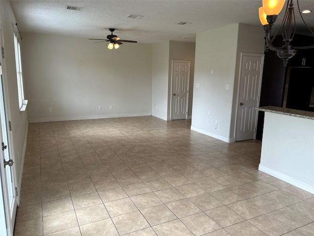 empty room featuring baseboards, visible vents, and a ceiling fan