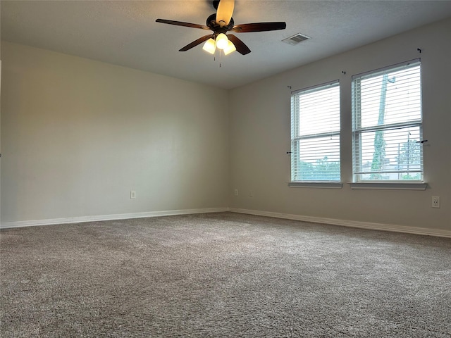 carpeted empty room with ceiling fan, a textured ceiling, visible vents, and baseboards