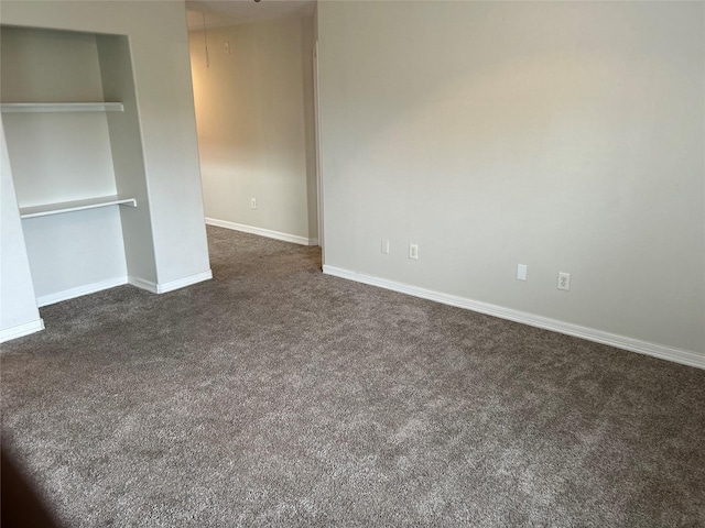 unfurnished bedroom with dark colored carpet, a closet, and baseboards