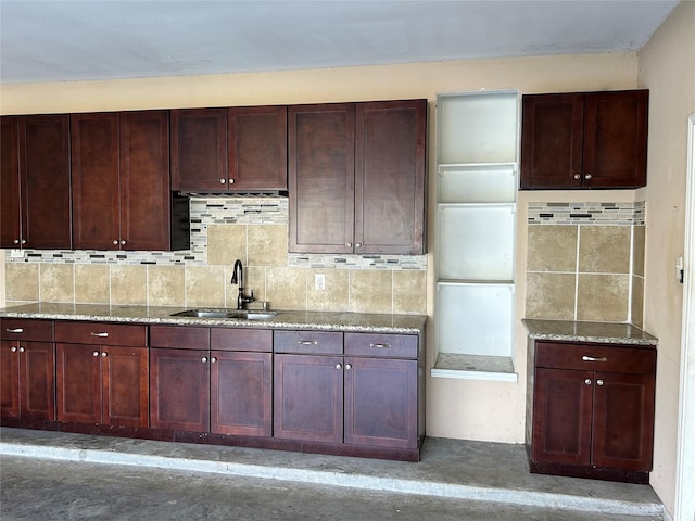 kitchen with dark brown cabinets, a sink, decorative backsplash, and light stone countertops