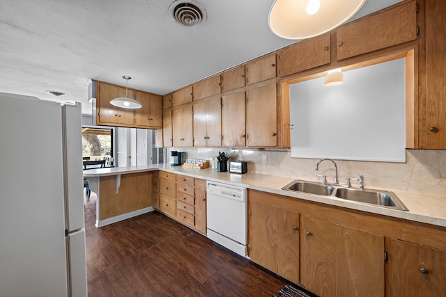 kitchen with light countertops, backsplash, a sink, white appliances, and a peninsula