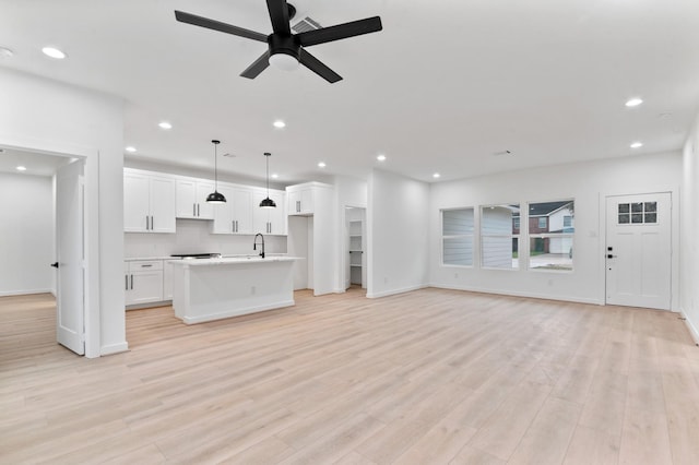 unfurnished living room featuring light wood finished floors, baseboards, a ceiling fan, and recessed lighting