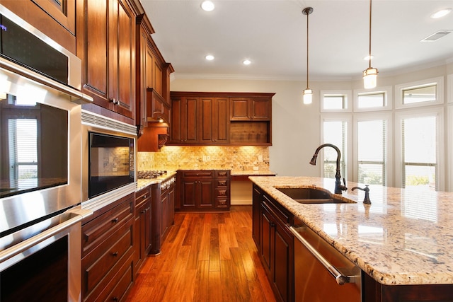 kitchen featuring visible vents, appliances with stainless steel finishes, ornamental molding, a sink, and backsplash