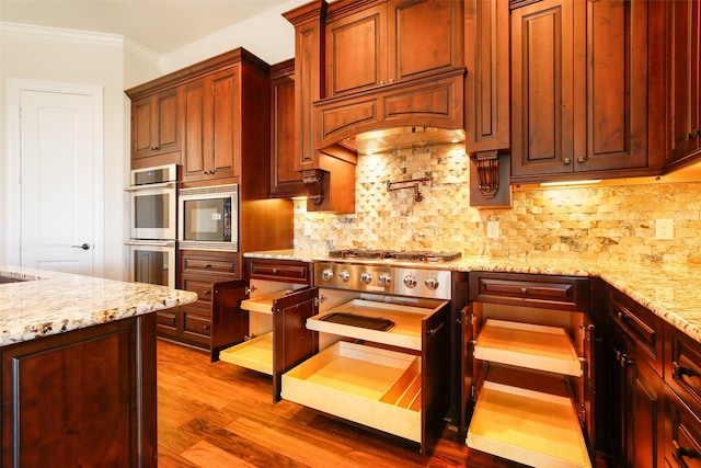 kitchen featuring crown molding, decorative backsplash, double oven, wood finished floors, and built in microwave