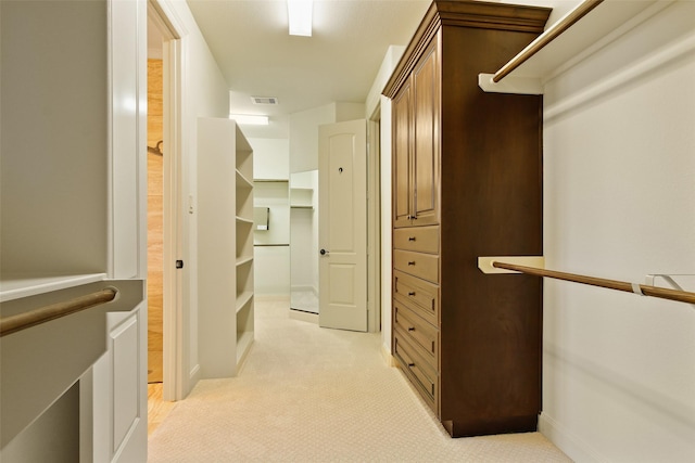 walk in closet with visible vents and light colored carpet