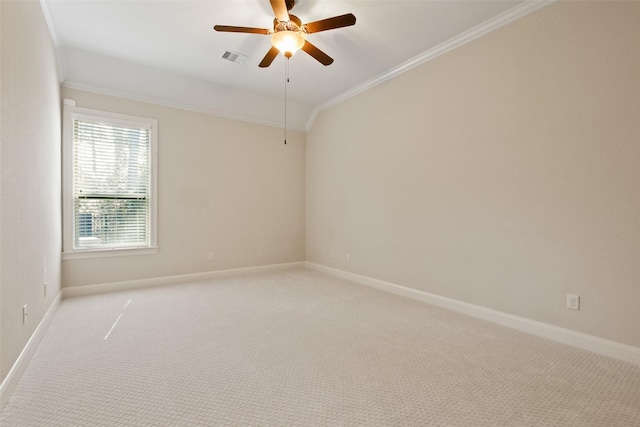 empty room with ceiling fan, light colored carpet, visible vents, baseboards, and ornamental molding