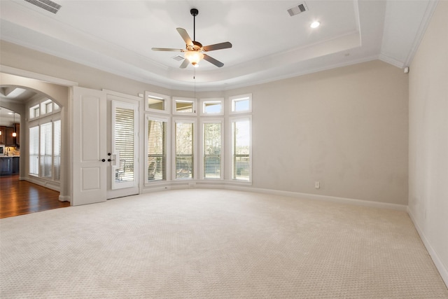 unfurnished room with ornamental molding, a raised ceiling, and visible vents