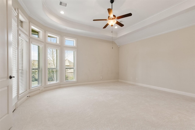 empty room with baseboards, visible vents, a raised ceiling, and light colored carpet