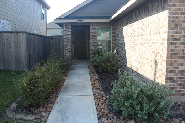 entrance to property featuring brick siding and fence