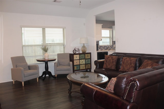 living area with lofted ceiling, visible vents, and dark wood finished floors