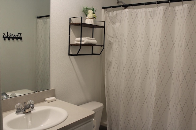 full bathroom featuring curtained shower, a textured wall, vanity, and toilet