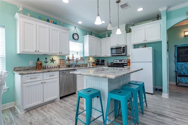 kitchen featuring a breakfast bar, visible vents, white cabinetry, ornamental molding, and appliances with stainless steel finishes