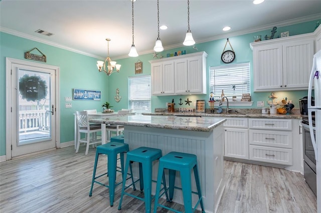 kitchen featuring a kitchen island, visible vents, white cabinets, and a sink