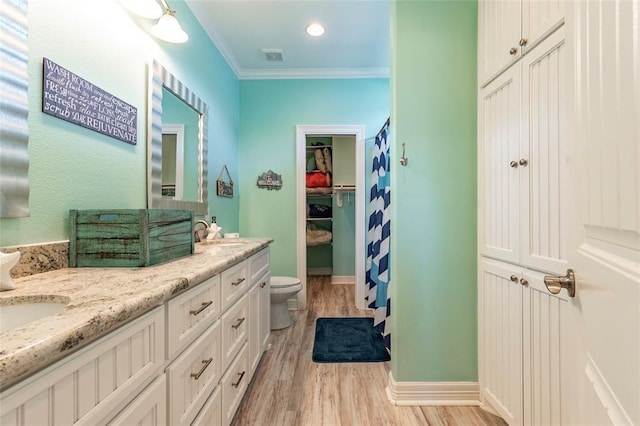 full bathroom featuring double vanity, toilet, ornamental molding, a sink, and wood finished floors