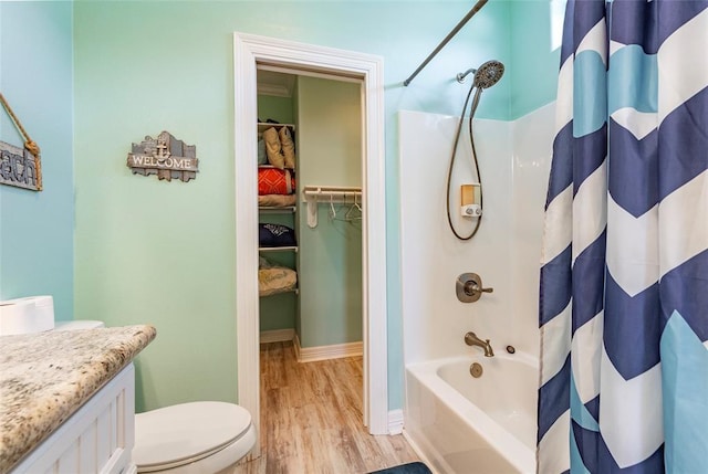 bathroom with toilet, wood finished floors, vanity, baseboards, and shower / bathtub combination with curtain