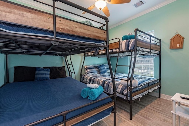 bedroom featuring baseboards, visible vents, wood finished floors, and ornamental molding