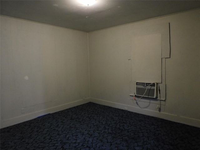 empty room with baseboards, dark colored carpet, and a wall mounted air conditioner