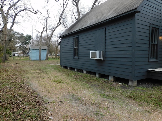 view of side of property with a shed, an outdoor structure, and a shingled roof