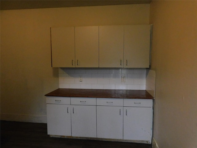 kitchen with baseboards, dark countertops, backsplash, and white cabinets