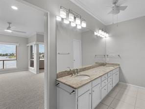 bathroom with crown molding, double vanity, ceiling fan, a sink, and baseboards