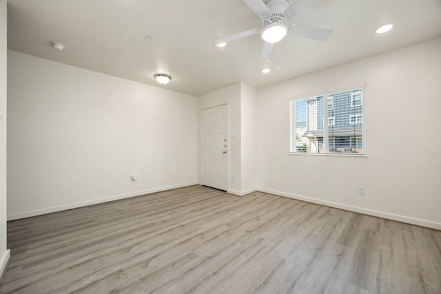 spare room with wood finished floors, a ceiling fan, and baseboards