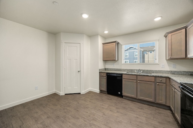 kitchen with black appliances, a sink, dark wood finished floors, and baseboards