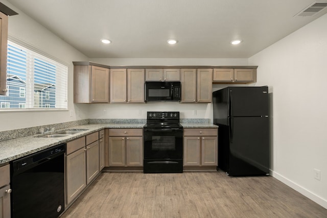 kitchen with black appliances, light wood-type flooring, a sink, and visible vents