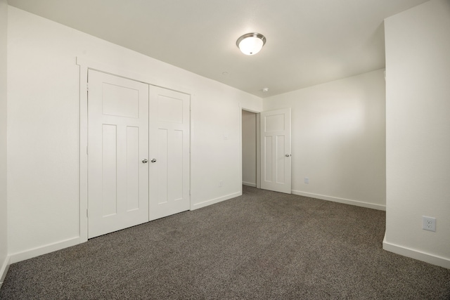 unfurnished bedroom with a closet, dark carpet, and baseboards