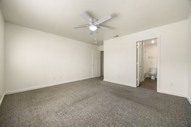 unfurnished bedroom with ensuite bathroom, dark carpet, visible vents, and baseboards