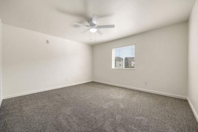 unfurnished room with ceiling fan, baseboards, and dark colored carpet