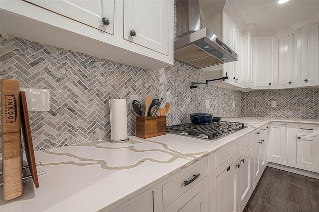 kitchen with stainless steel gas cooktop, wall chimney range hood, backsplash, and white cabinets