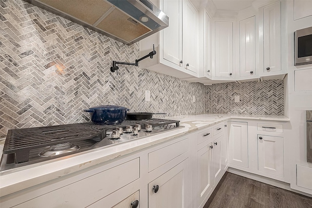 kitchen featuring stainless steel appliances, white cabinets, backsplash, wall chimney exhaust hood, and dark wood finished floors