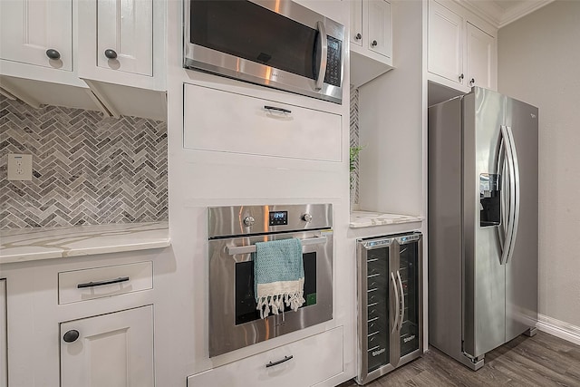 kitchen with light stone counters, beverage cooler, white cabinetry, appliances with stainless steel finishes, and dark wood finished floors