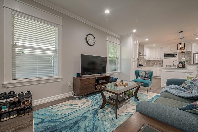 living area with light wood-type flooring, crown molding, baseboards, and recessed lighting