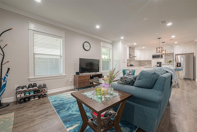 living area featuring light wood-style flooring, visible vents, baseboards, and ornamental molding