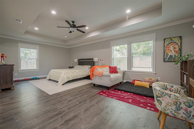 bedroom featuring a tray ceiling, wood finished floors, visible vents, and crown molding