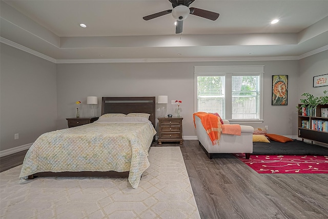 bedroom featuring baseboards, a raised ceiling, and wood finished floors