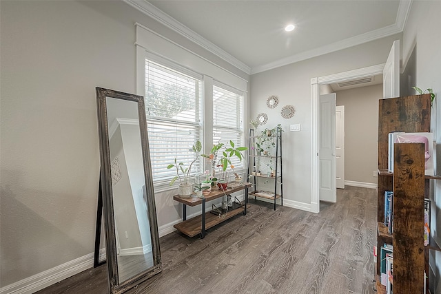 interior space featuring baseboards, visible vents, wood finished floors, and ornamental molding